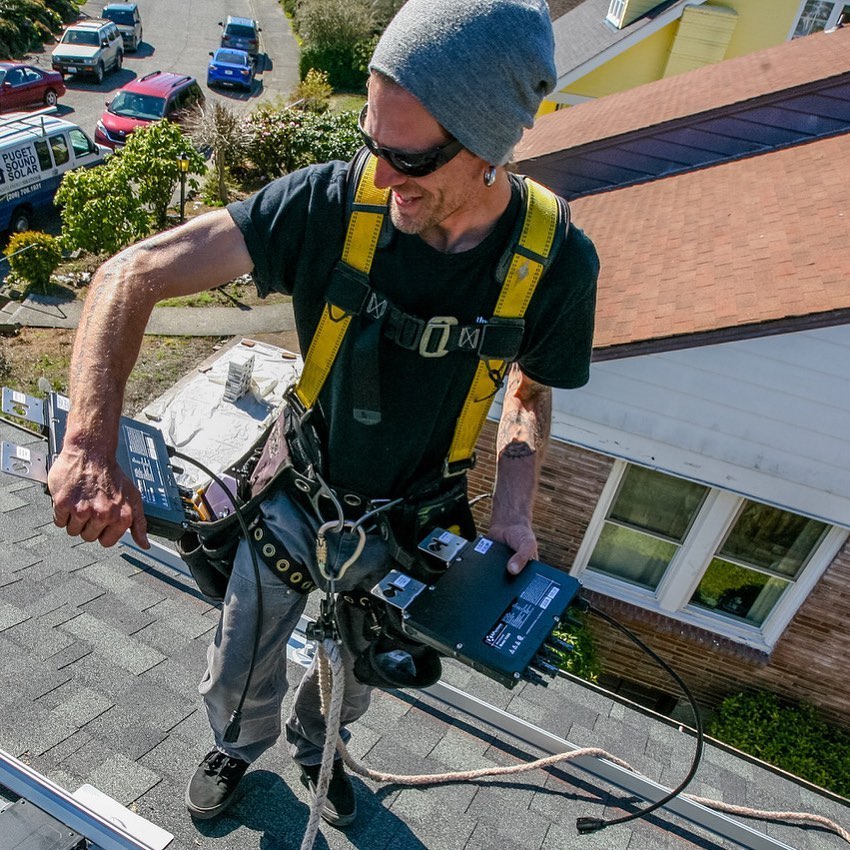 Hombre parado sobre el tejado de una casa instalando un inversor solar