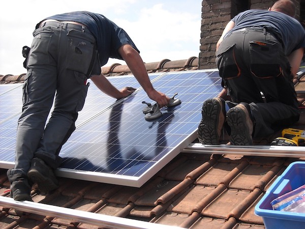 hombres parados en tejado dando mantenimiento a sistema fotovoltaico